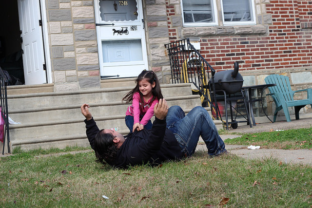 Osama Mohammed and his daughter, Yusra, play in the front lawn of their Northeast Philadelphia home. The family arrived in the United States as refugees earlier this year after fleeing their home in a Damascus suburb. Photo by Razi Syed.